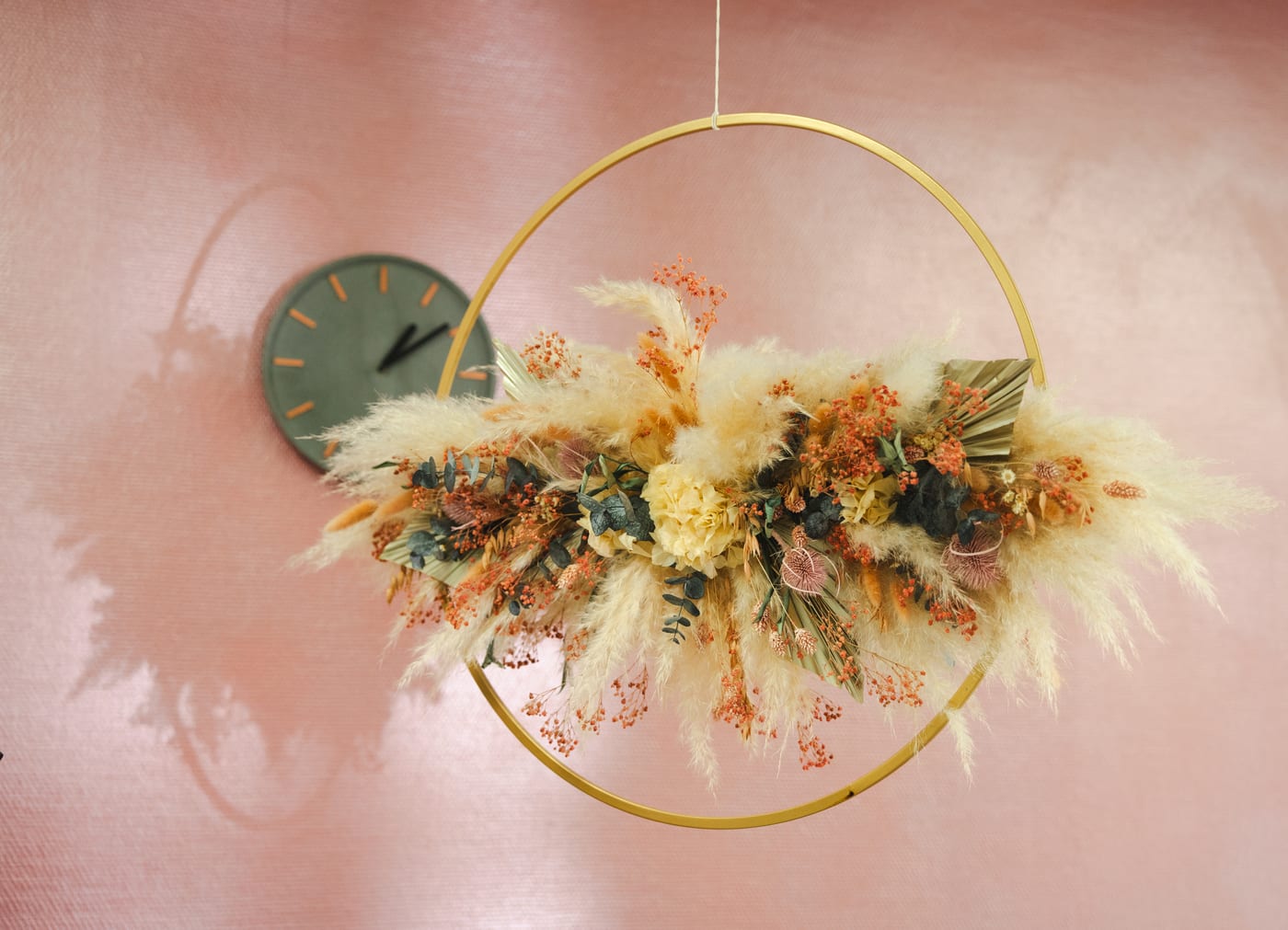 Trockenblumenkranz vor rosa Wand im Salon