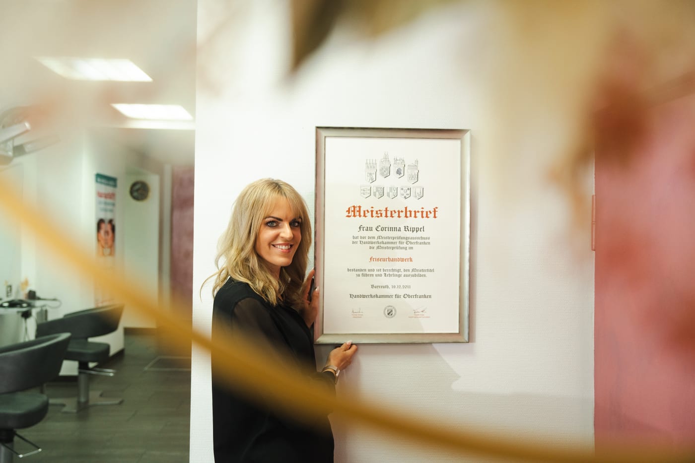 Corinna Rippel vor ihrem Meisterbrief der Handwerkskammer
